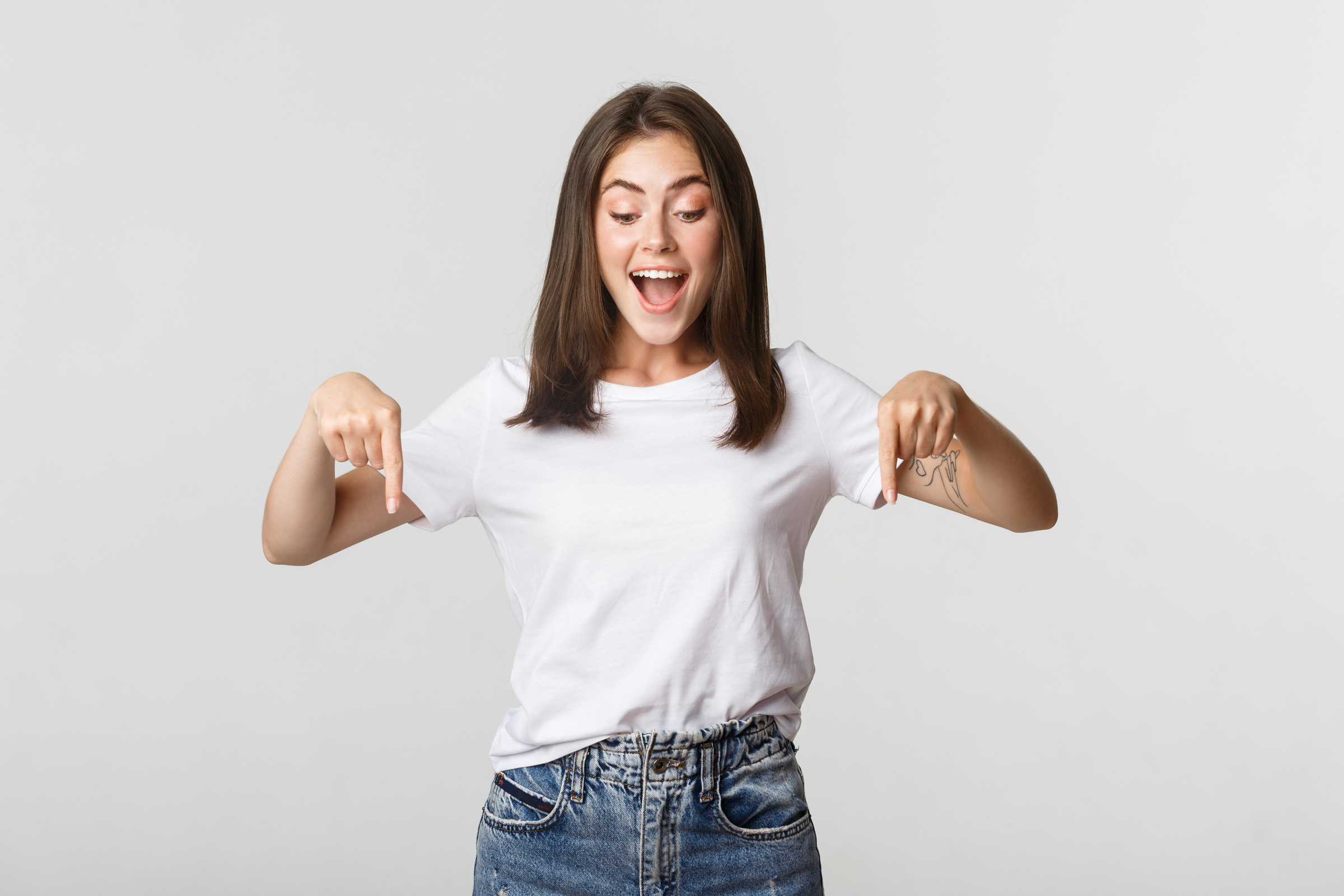 Excited Happy Brunette Girl, Looking and Pointing down with Amused Smile