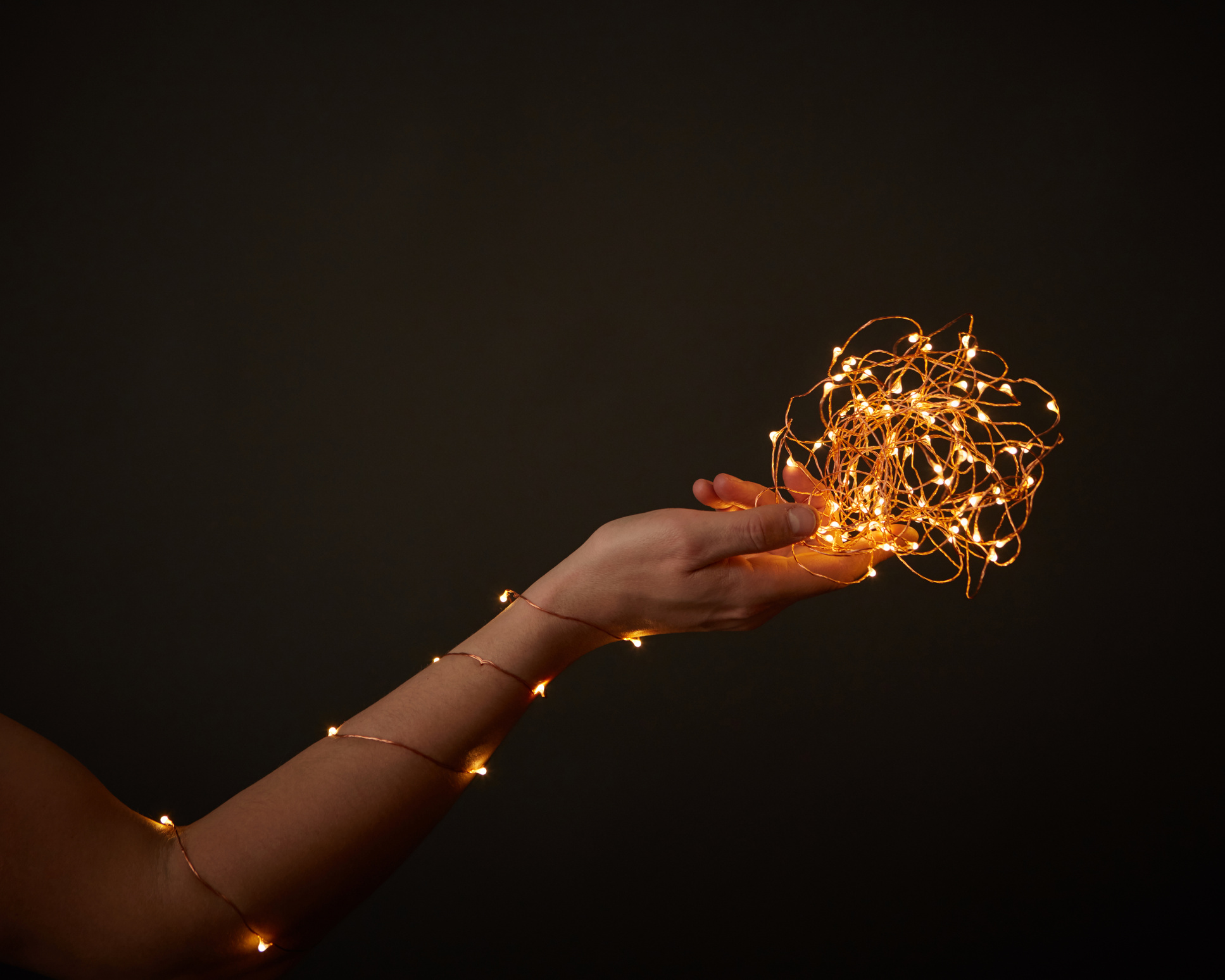 Woman's Hand Decorate with Yellow Garlands around a Black Background with Copy Space. Christmas