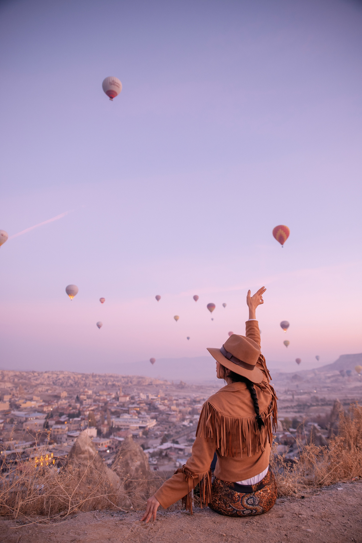 Woman Sitting and Waving Hand to Hot Air Balloons