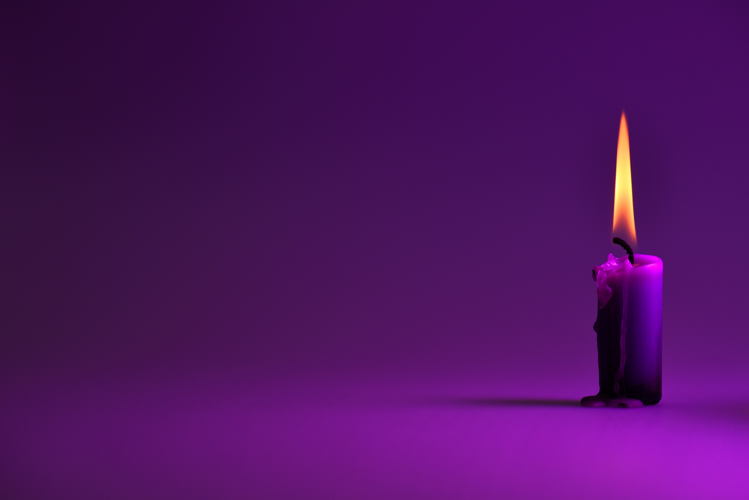 purple candle on a purple background, a bright orange light.